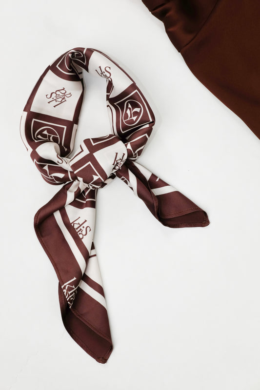 The Emblem Kalisa Logo Silk Scarf in Espresso shown tied as a neck accessory.
