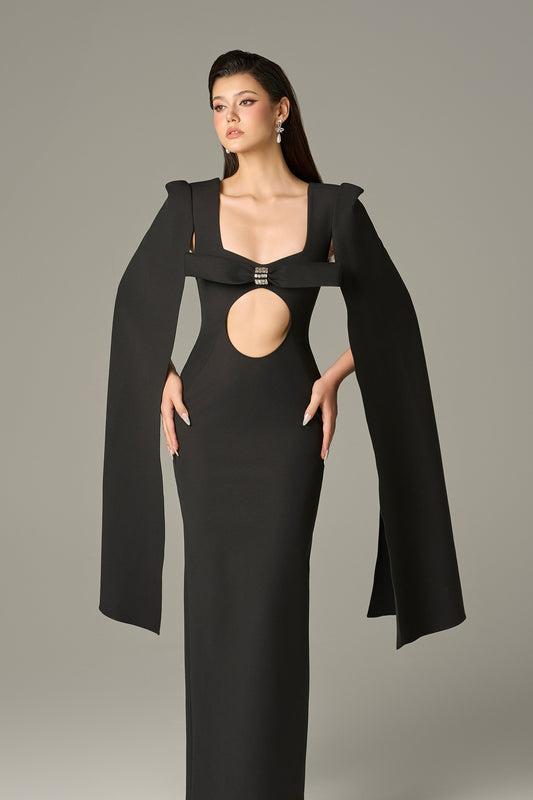 The Black Maxi Dress stuns with a crystal-embellished bow, bold circular cutout and flowing cape sleeves.