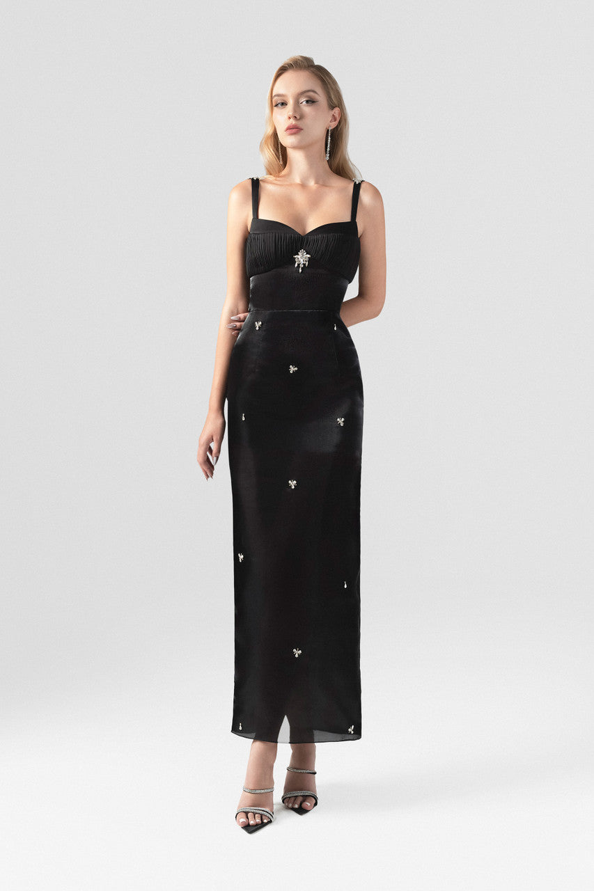 The black dress with classic square neckline, sleeveless design, and intricate orchid appliqués.