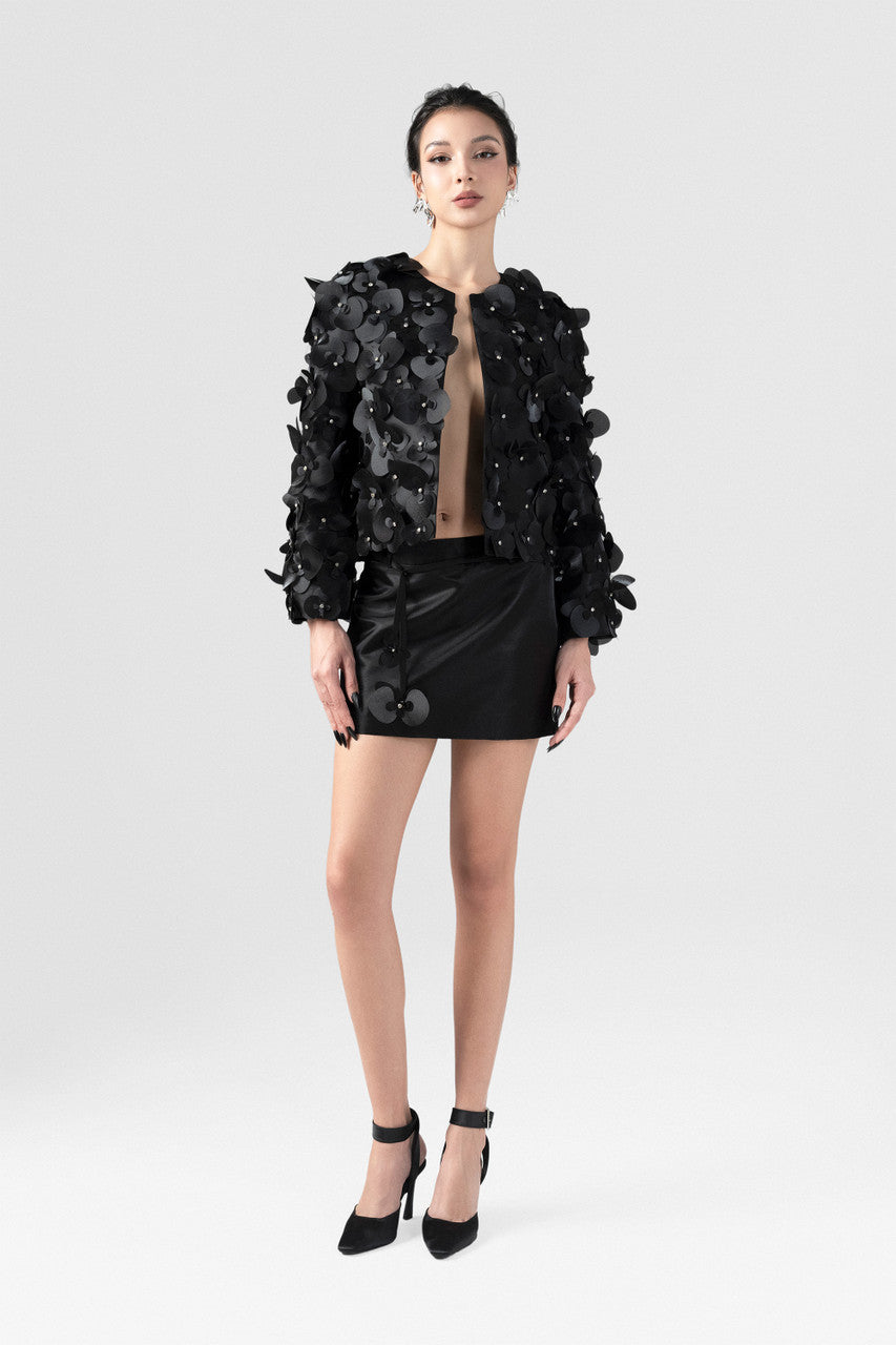 Cropped black jacket in satin, with long sleeves and orchid embellishments.