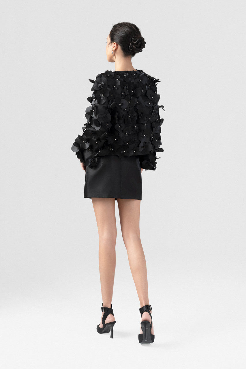 Cropped black jacket in satin, with long sleeves and orchid embellishments.