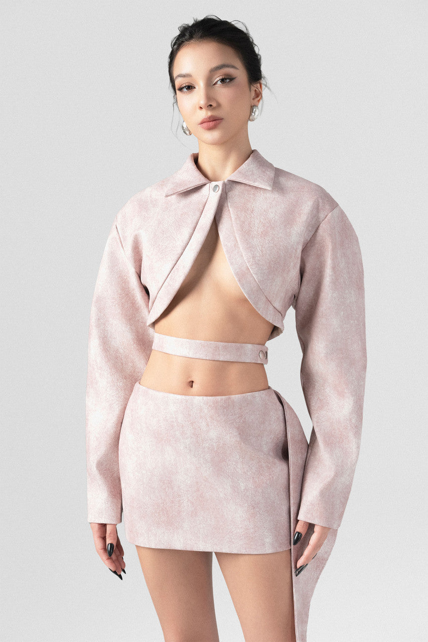 A pink leather set featuring a slim-fit blazer with oversized sleeves, an inverted V-cut neckline, and a matching mini skirt with a side flap.