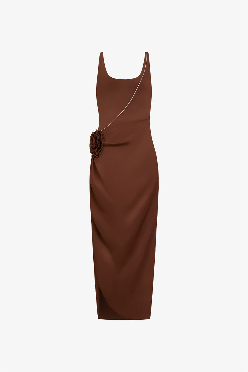 The brown silk maxi dress, detailed with a scoop neckline, hand-sewn rose accent, and stone chain embellishments.