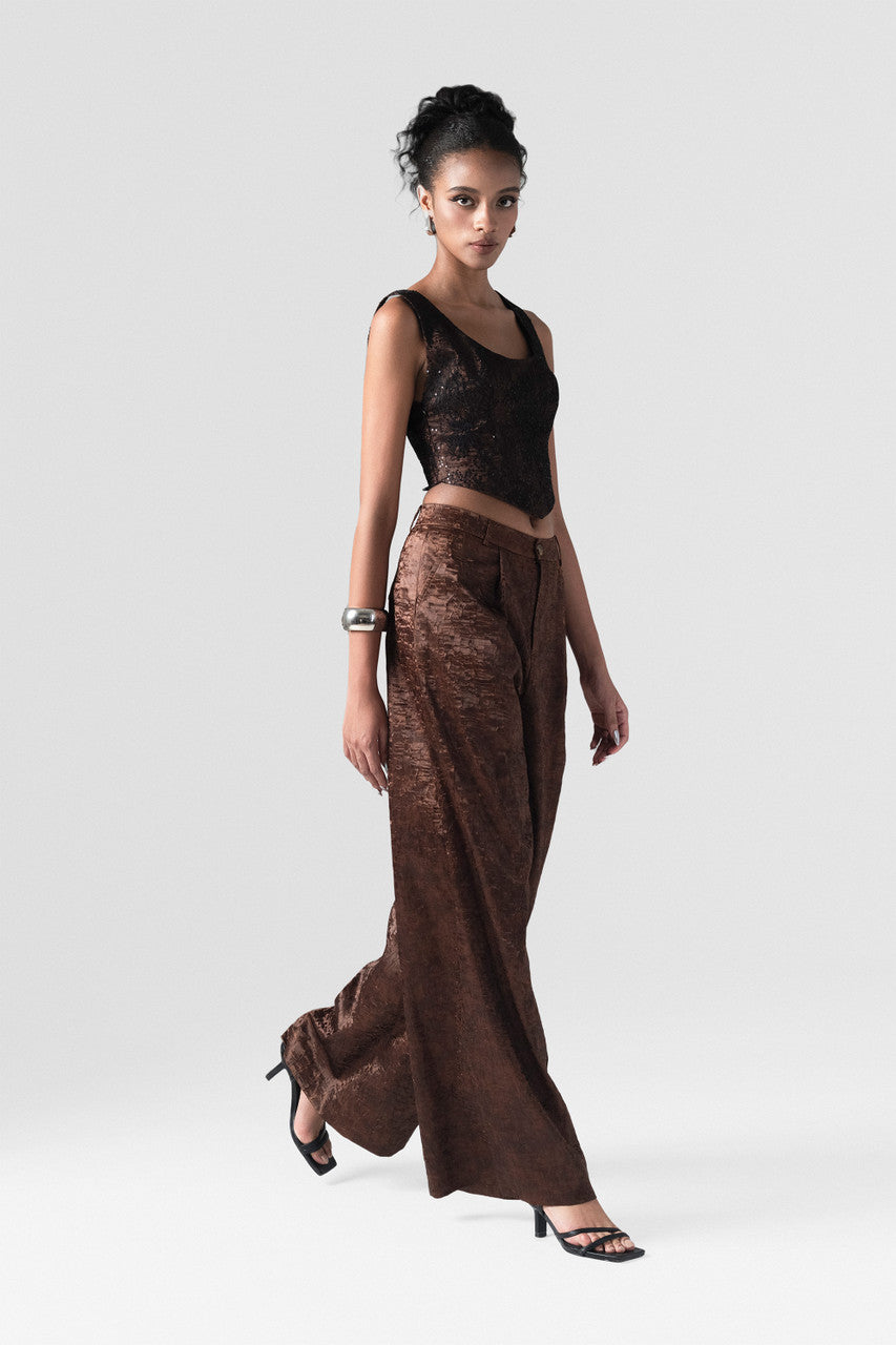 The brown set in satin, featuring a fitted corset crop top with a lace-up back and high-waisted, wide-leg trousers.