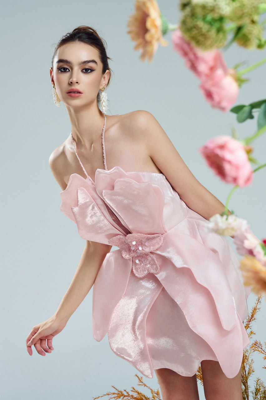 A pink mini dress in silk organza. Premium crystal embellishments, orchid petal-inspired cutouts, and string-neck design.