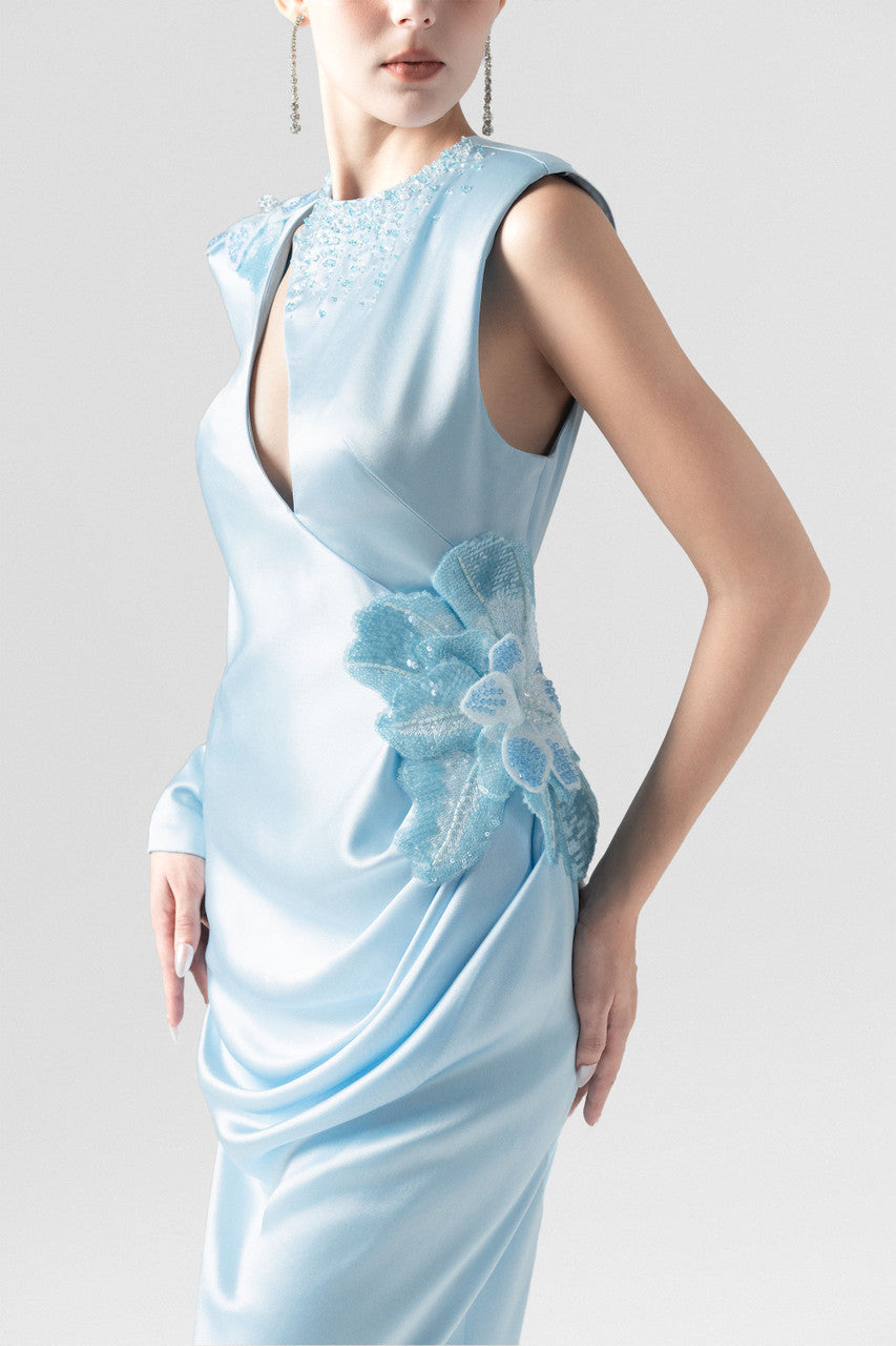 A blue silk maxi dress, with sequin floral accents and asymmetrical design.