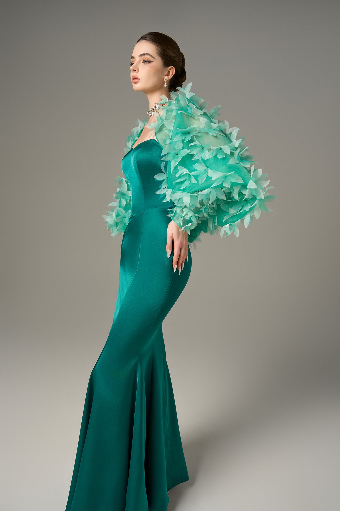 The Fishtail Gown stuns with emerald silk finish and a floral-embellished organza cape.