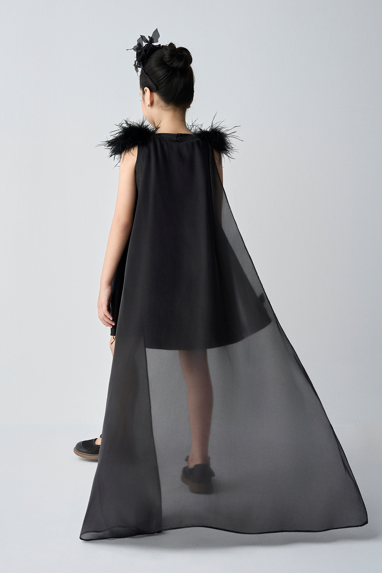 Black dress with feathered shoulders on a gray background