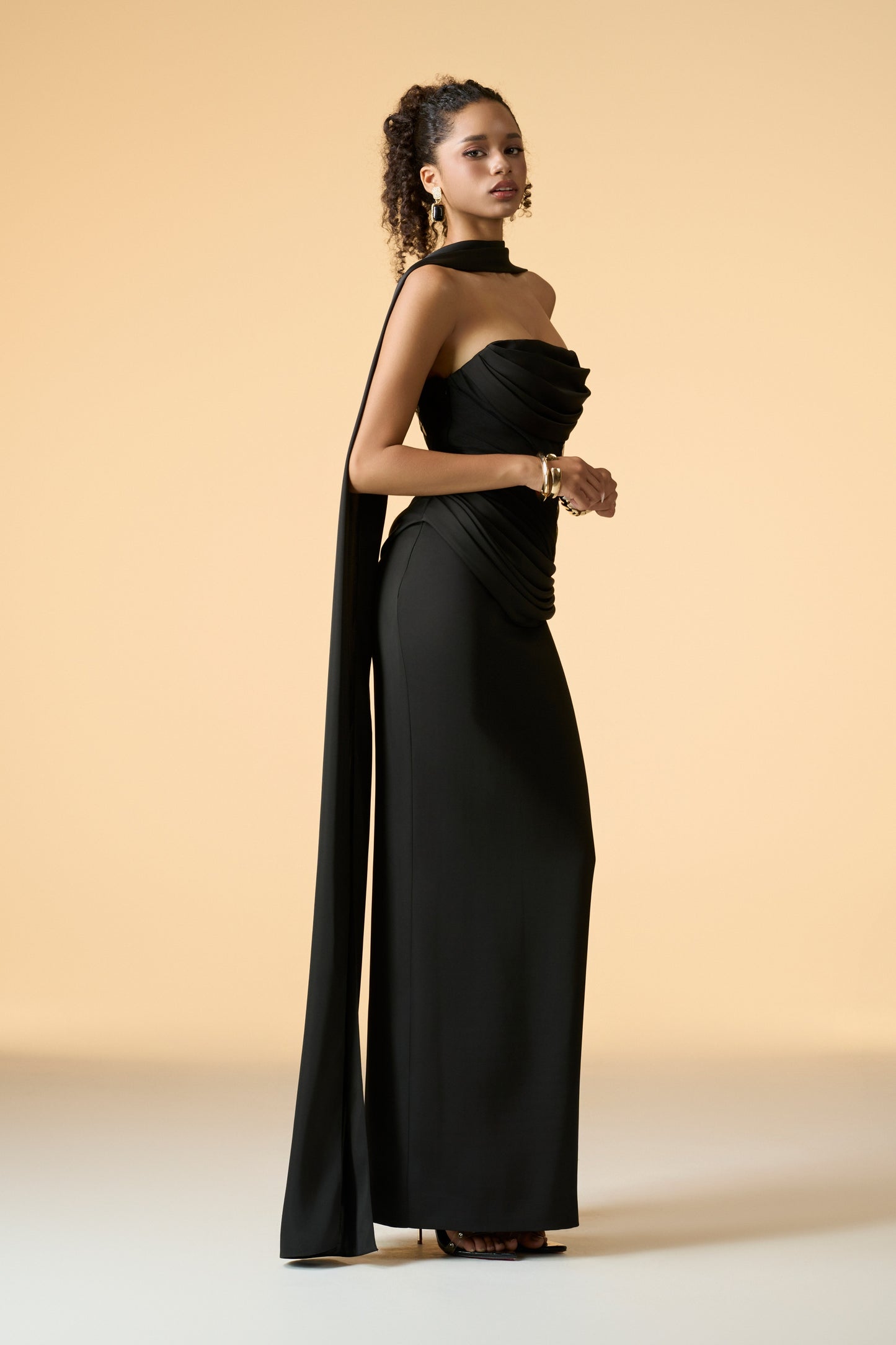The back view of a rose gold floor-length maxi dress, showcasing its strapless design and flowing silhouette.