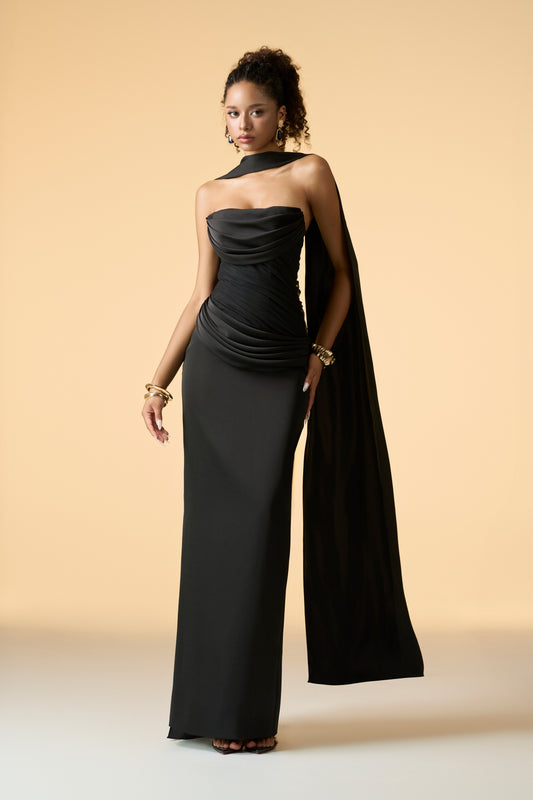 A rose gold floor-length maxi dress with a strapless bandeau neckline and ruffled ruching detail across the bodice. A coordinating neck scarf is draped elegantly.