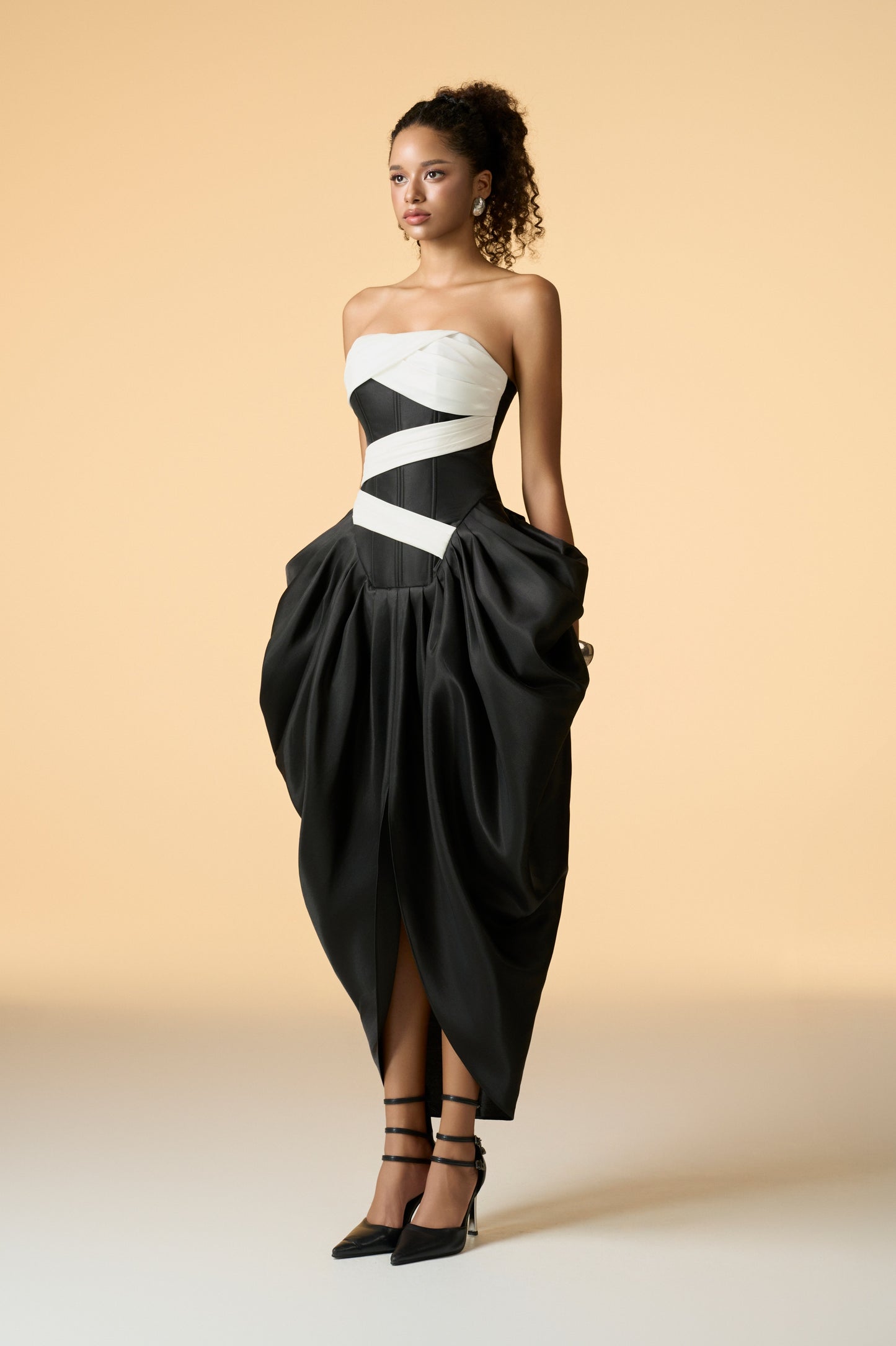 A striking fuchsia pink strapless maxi dress with a bandeau neckline and a corset bodice. The dress features an asymmetrical design with a white band across the chest and waist, and a flared skirt with side volume and a center slit.