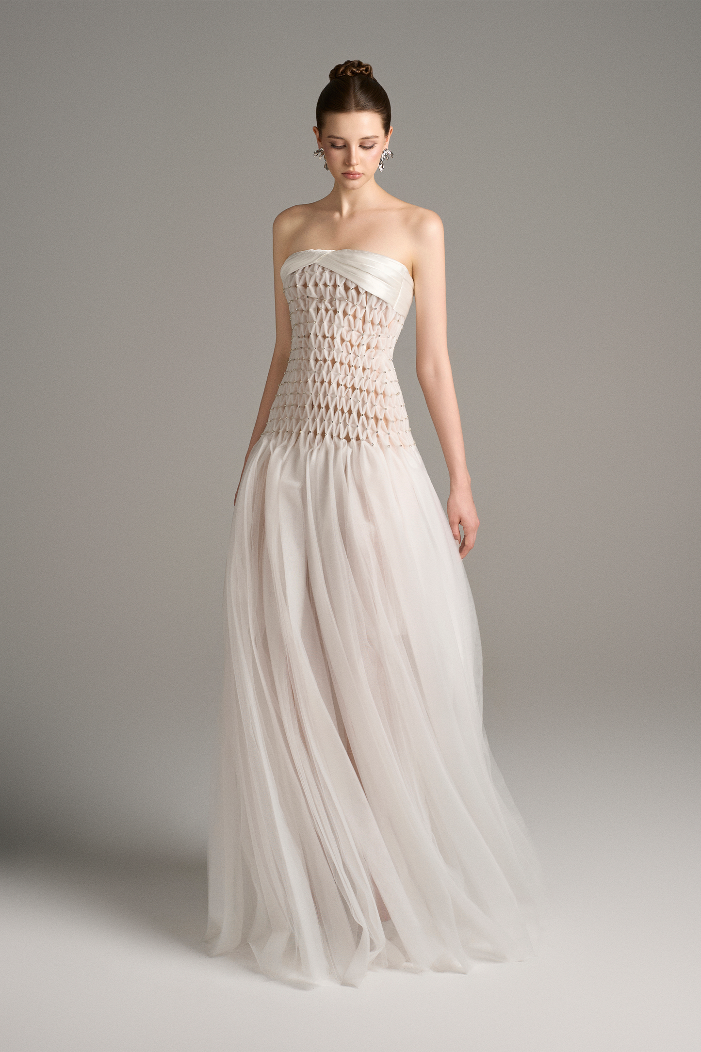 Angled front view of strapless drop waist maxi dress with sheer criss-cross bodice and tulle skirt