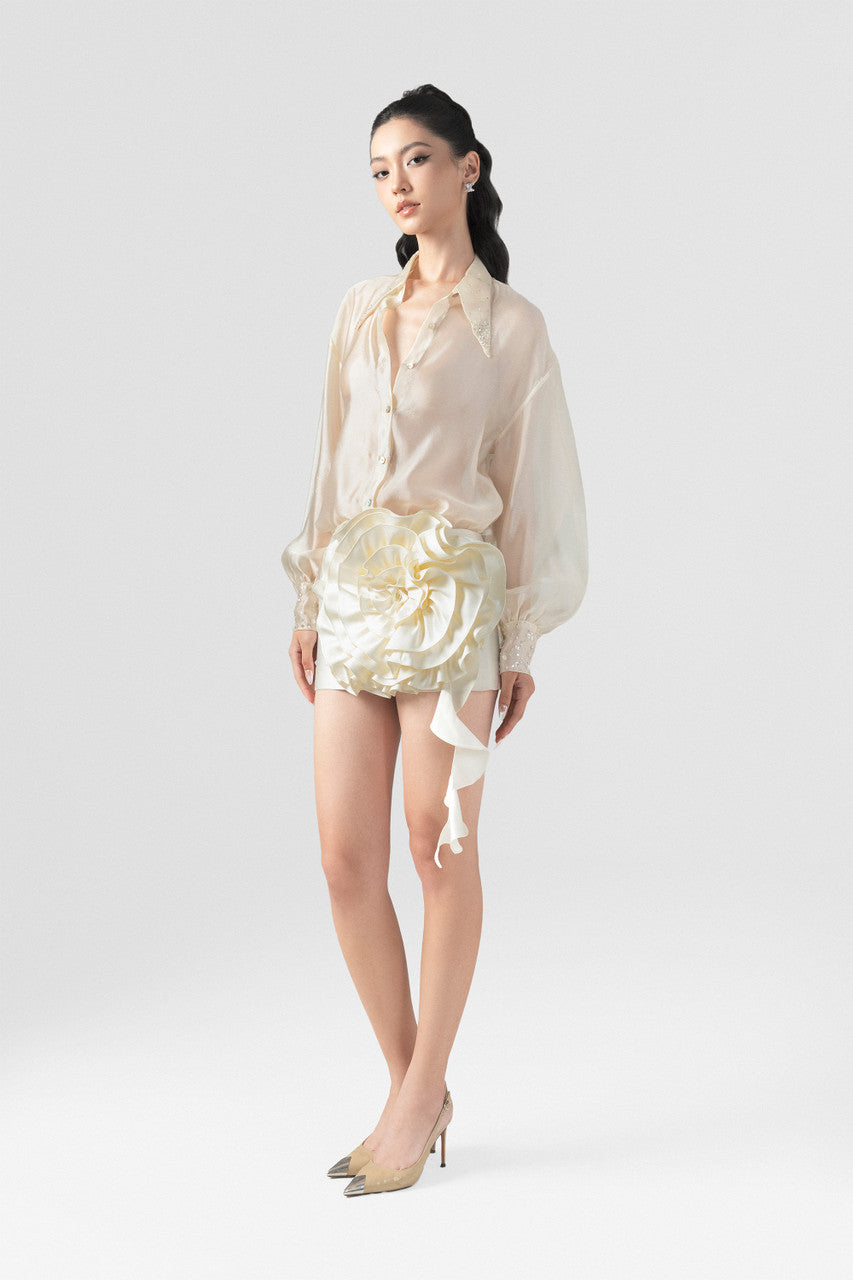 A beige set, featuring a silk shirt with beading on the collar, cuffs and a bodycon mini skirt with a large floral accent.