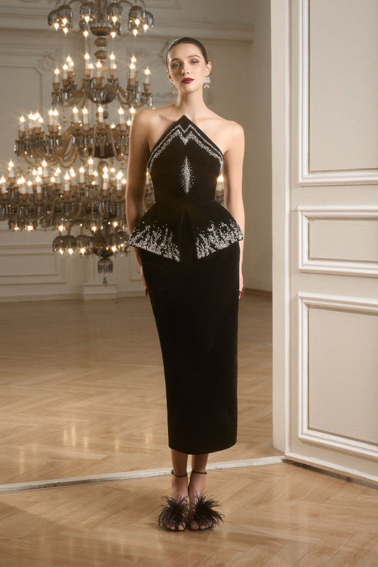 Black evening dress in velvet with a peplum and form-fitting skirt.