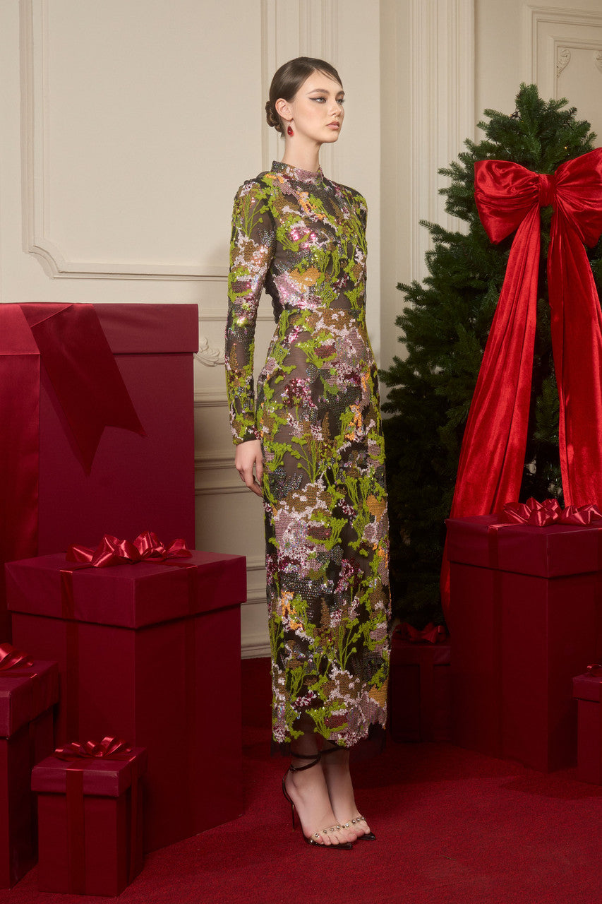 The green sequin maxi dress, featuring a fitted bodycon silhouette, a high neckline, and a transparent mesh back with pleated details.