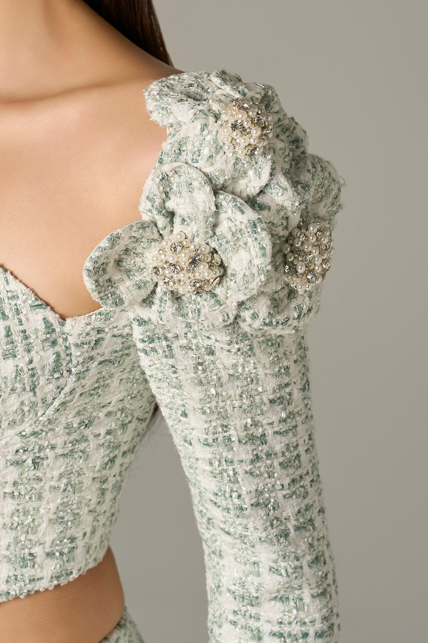 a set in mint green tweed, with a crop top and high-waisted flared trousers.
