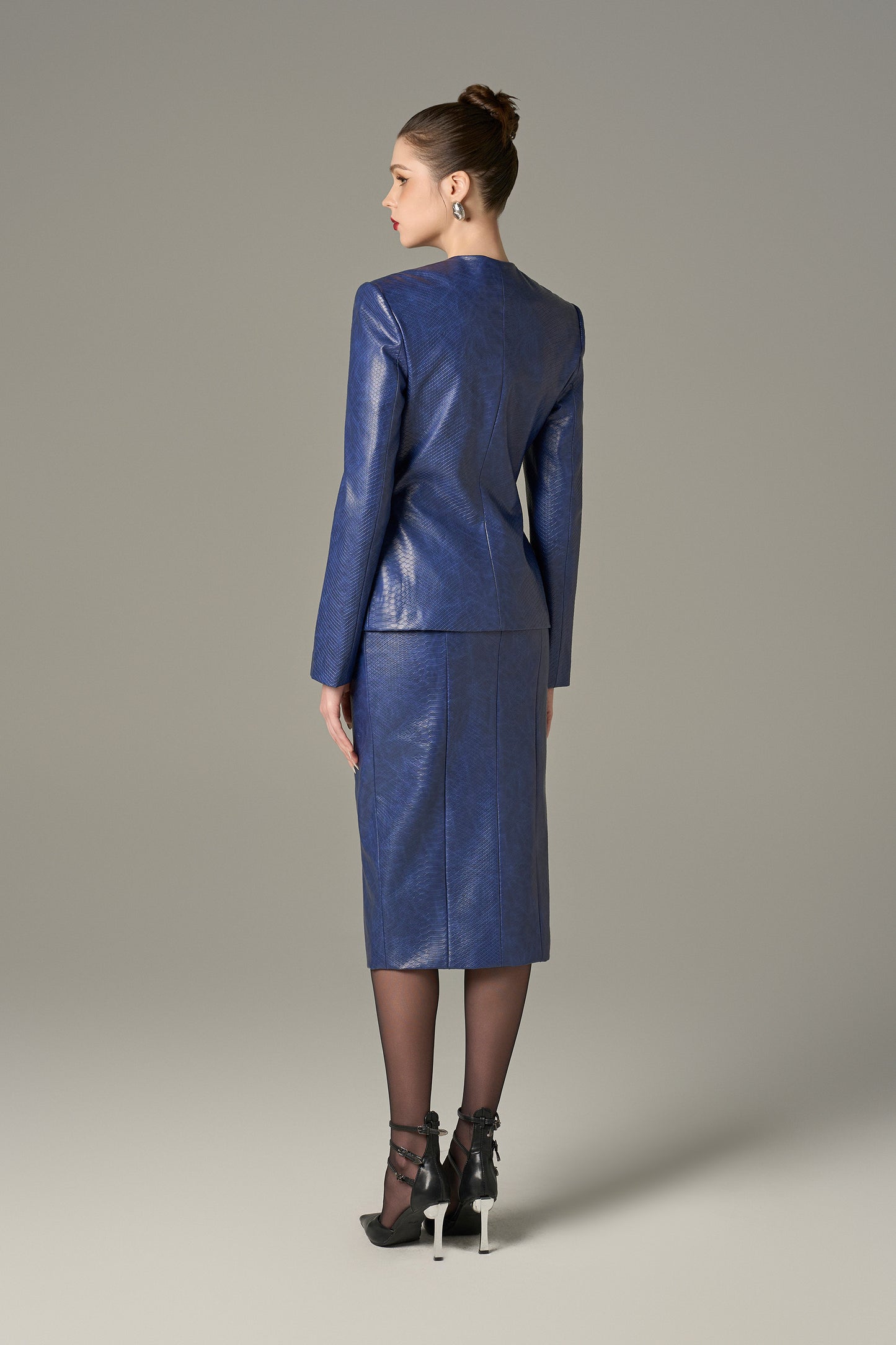 A navy set in crocodile-patterned leather, featuring a structured jacket and a pencil skirt.