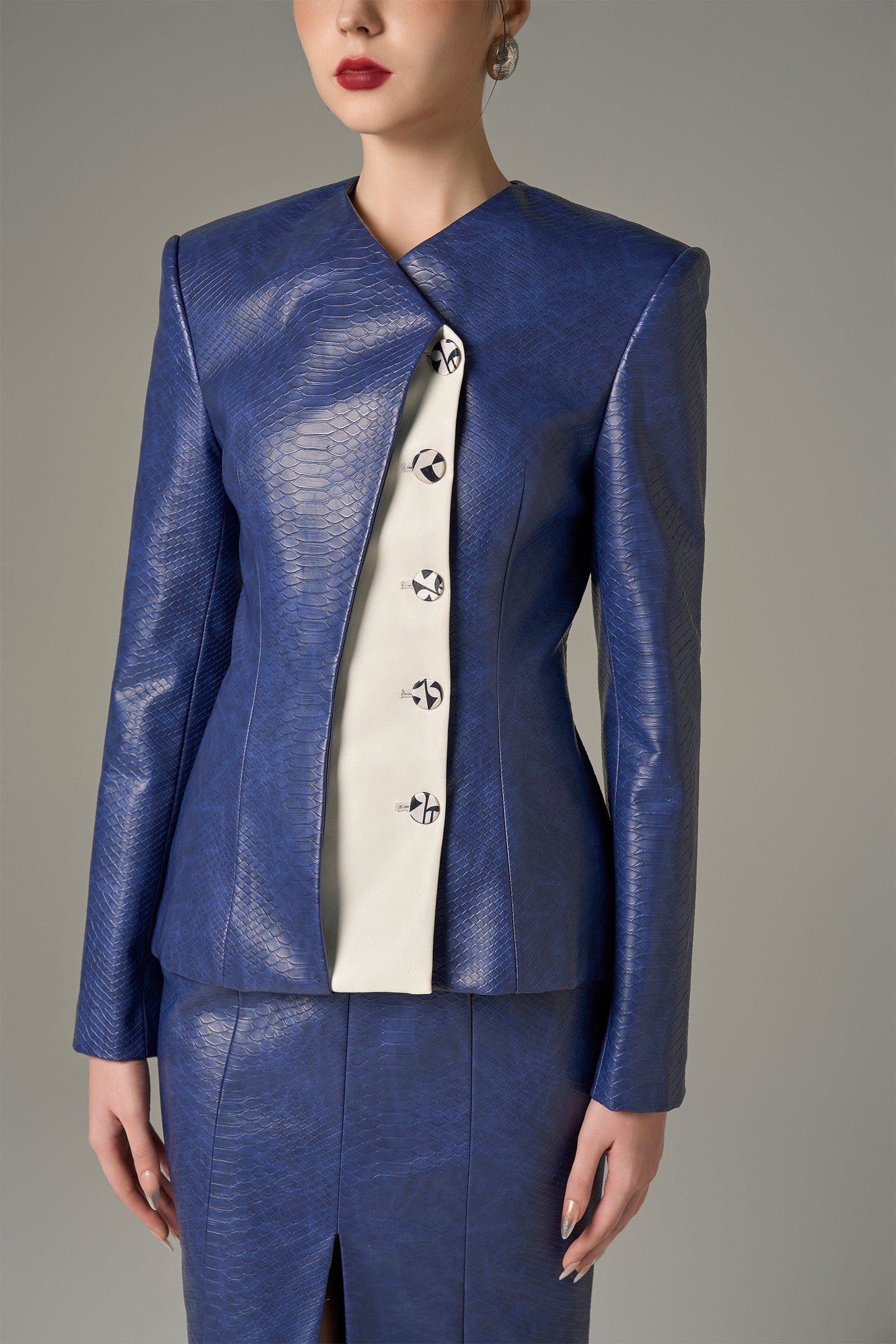 A navy set in crocodile-patterned leather, featuring a structured jacket and a pencil skirt.