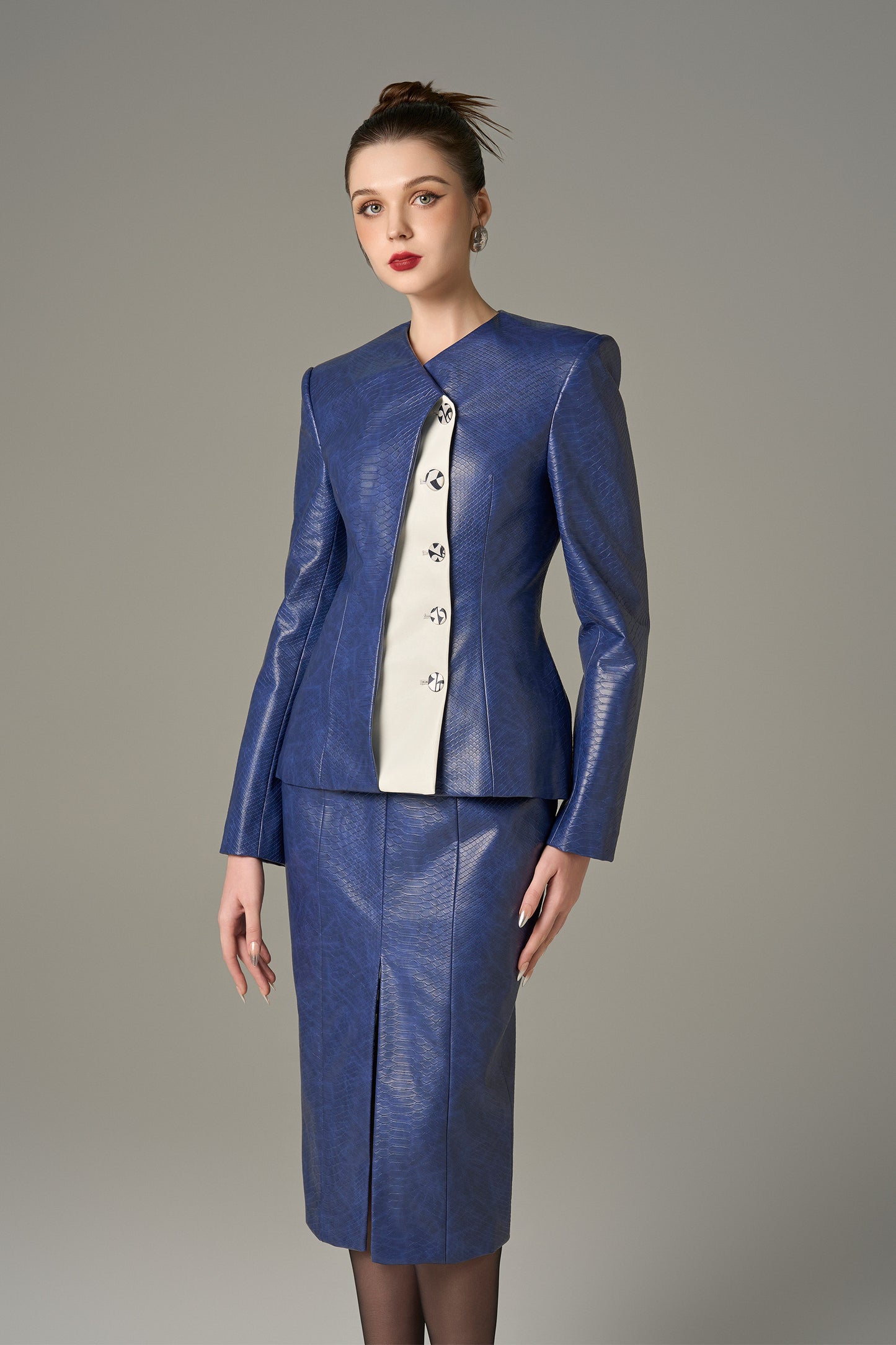 A navy set in crocodile-patterned leather, featuring a structured jacket and a pencil skirt.