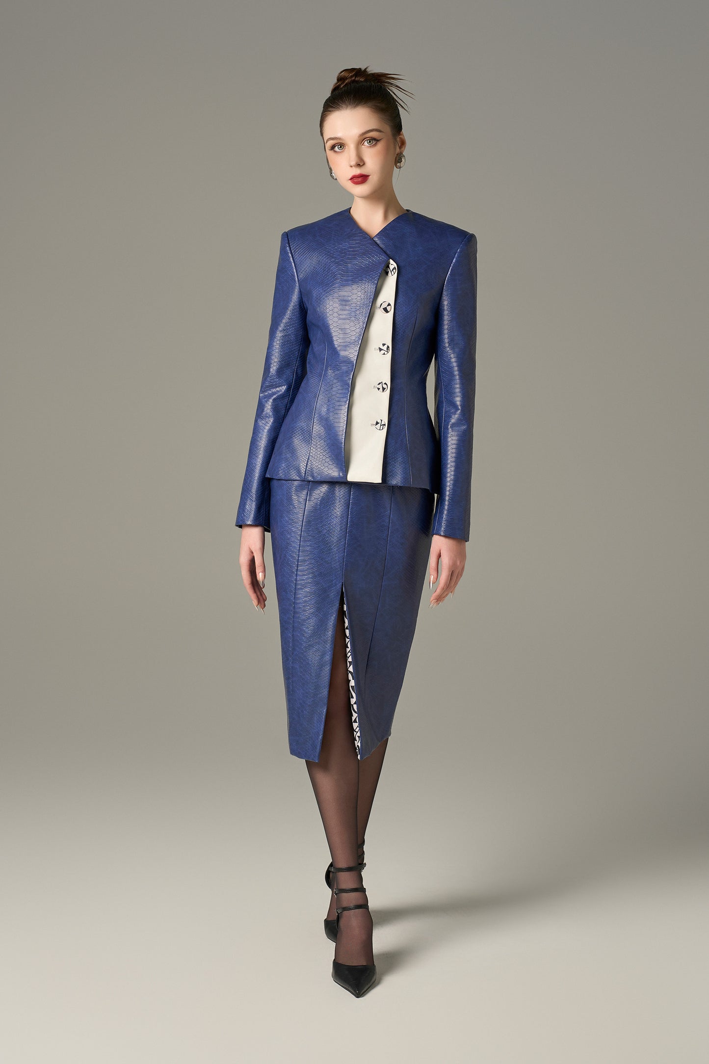 A navy set in crocodile-patterned leather, featuring a structured jacket and a pencil skirt.