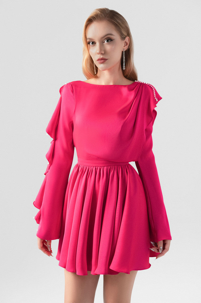 The pink silk mini dress, featuring daring open-back design, flowing pleats and ruffled detailing.