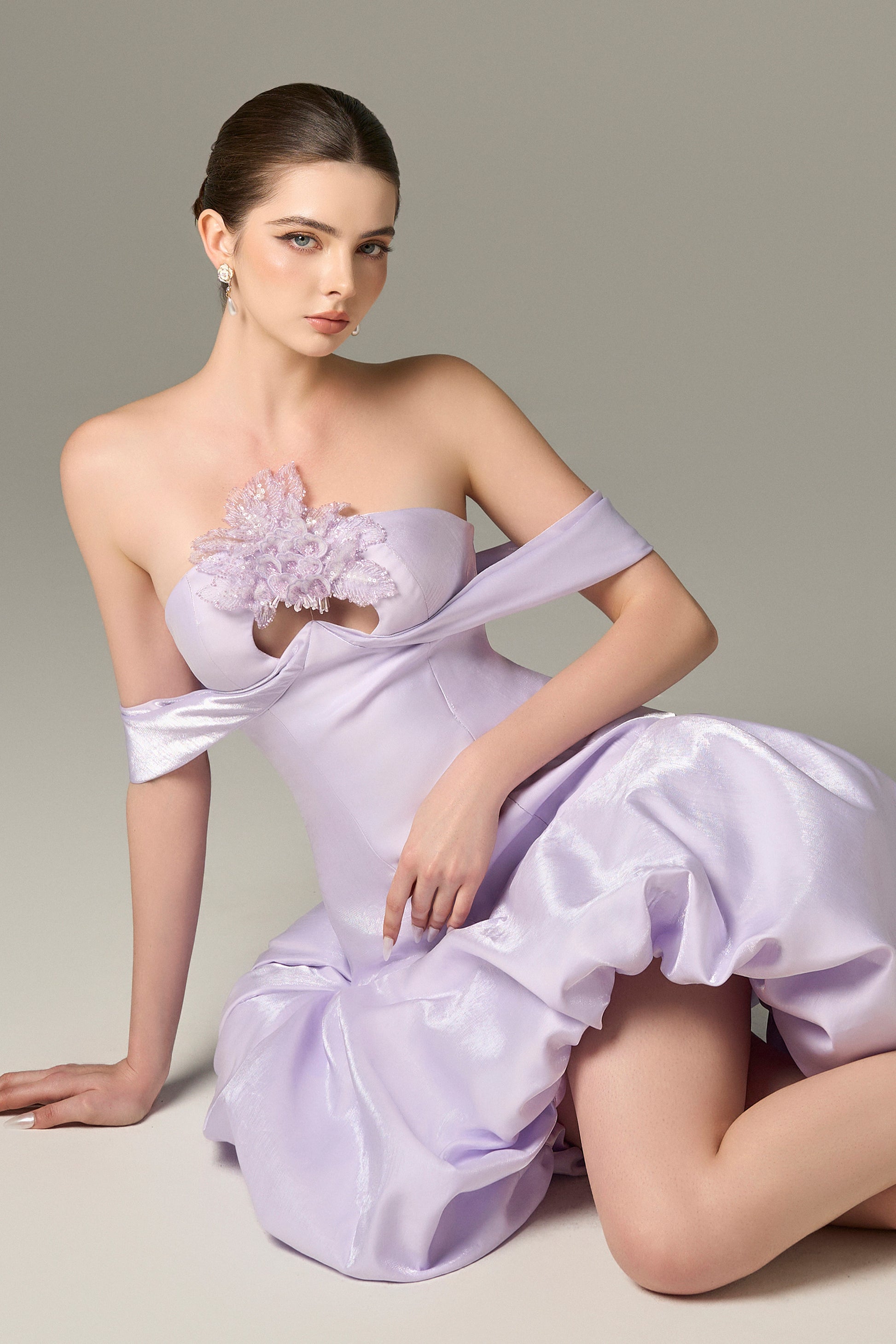 The Purple Drop Mini Dress stuns with off-shoulder draped straps, a voluminous puff skirt and sequin floral details.
