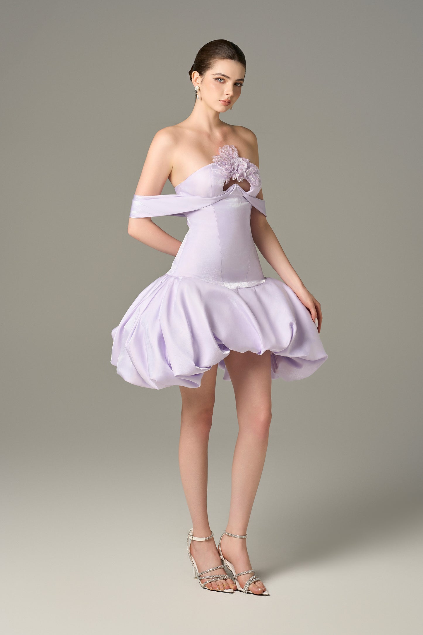 The Purple Drop Mini Dress stuns with off-shoulder draped straps, a voluminous puff skirt and sequin floral details.