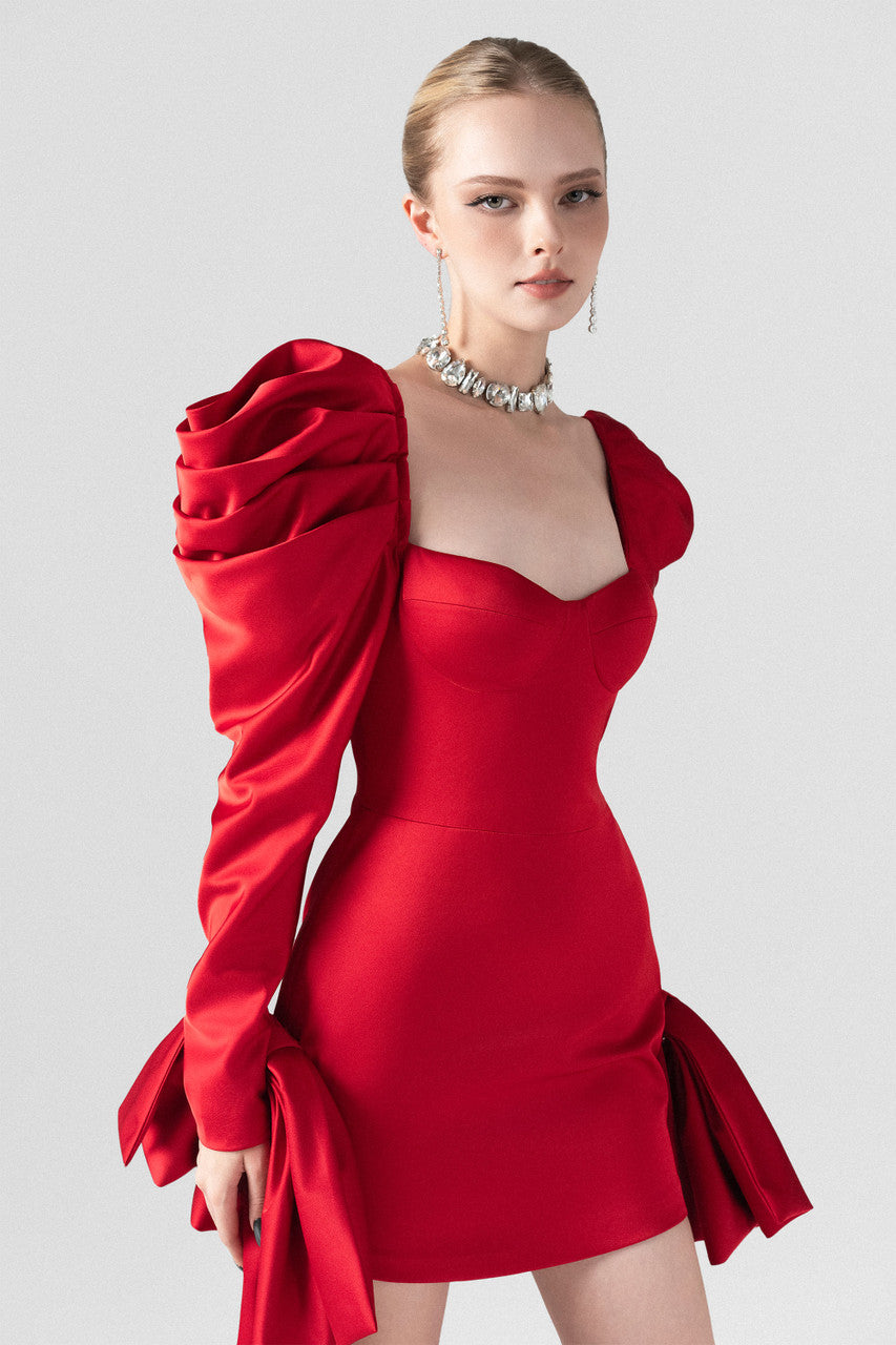 The red silk mini dress, with bust cup bodice, puffed sleeves and two crafted bows at the hips.