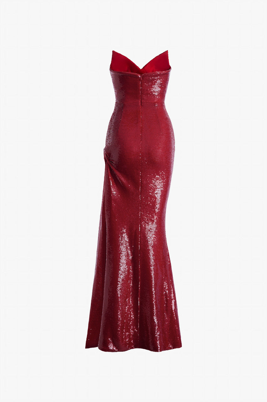 Red evening dress in sequin, with a cat-eye neckline and a thigh-high slit with ruffled details.
