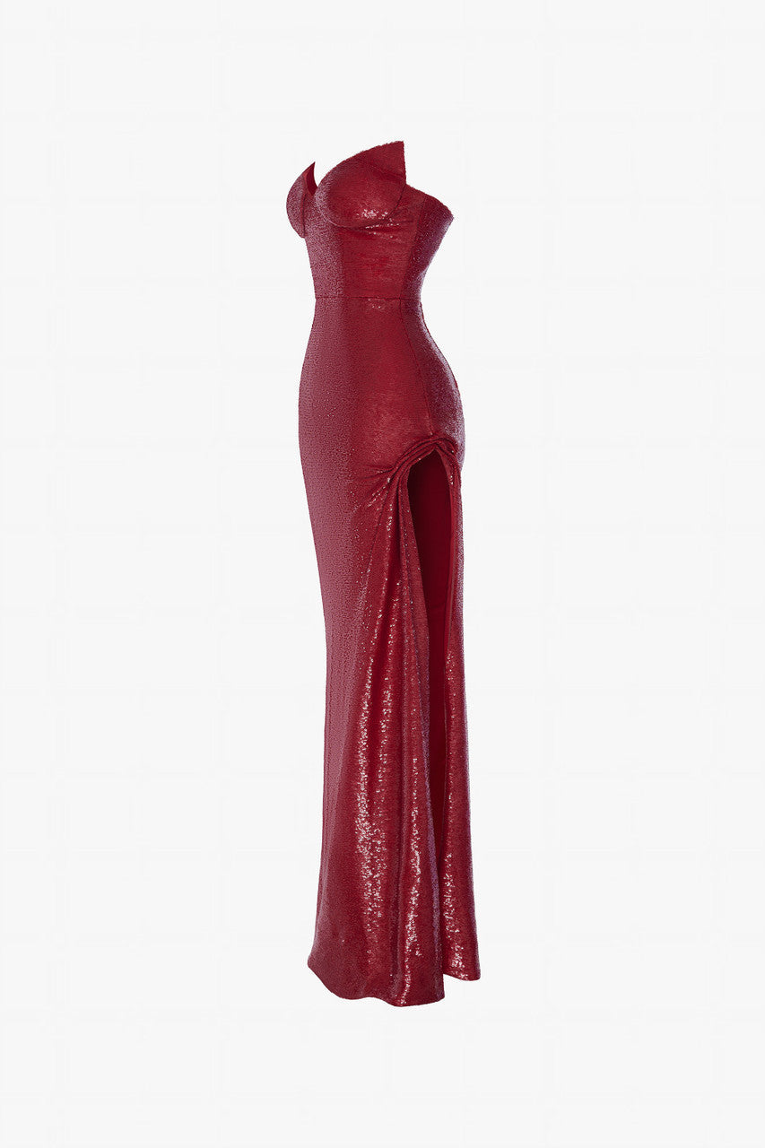 Red evening dress in sequin, with a cat-eye neckline and a thigh-high slit with ruffled details.