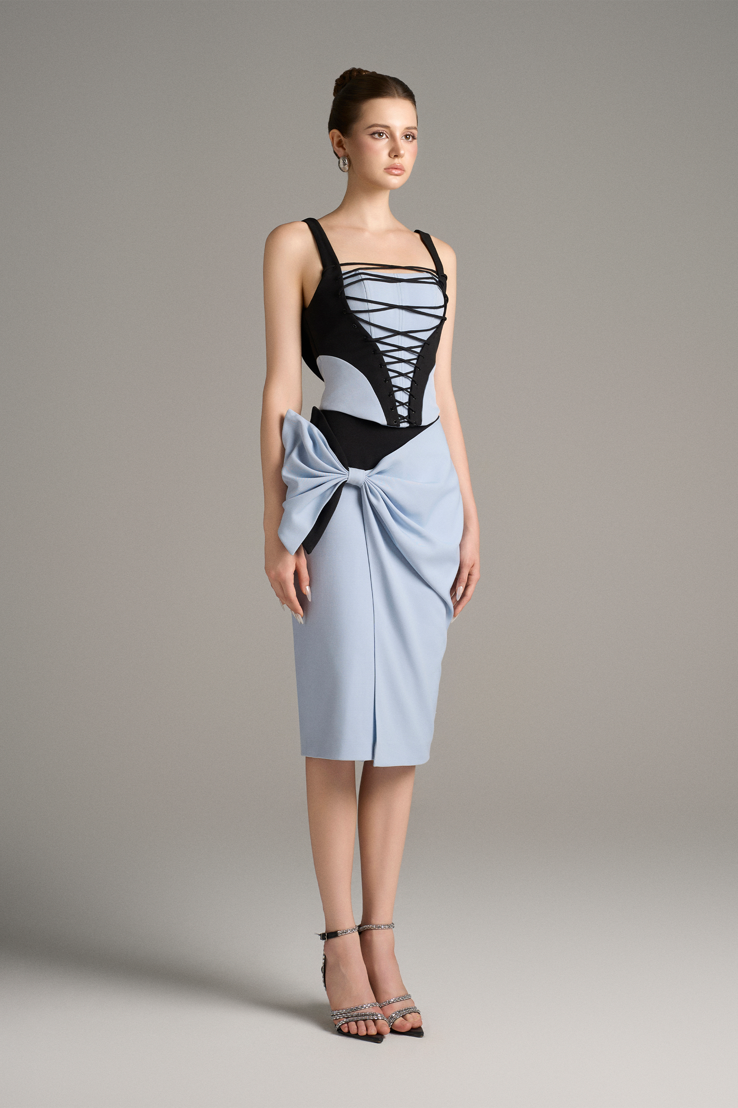 Model wearing a black and blue dress with a bow detail on a plain background