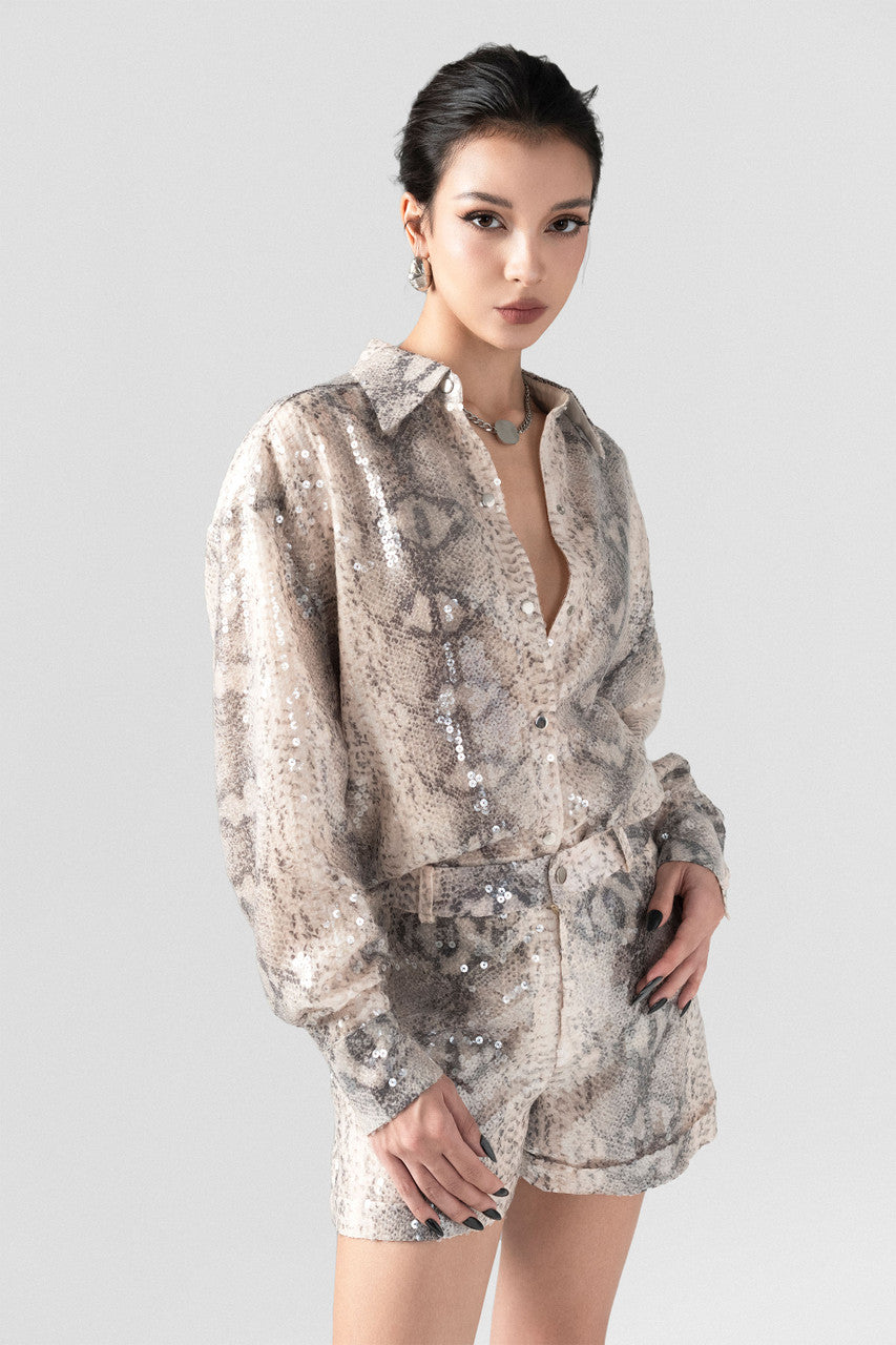 A sequin oversized shirt paired with snakeskin beige shorts.