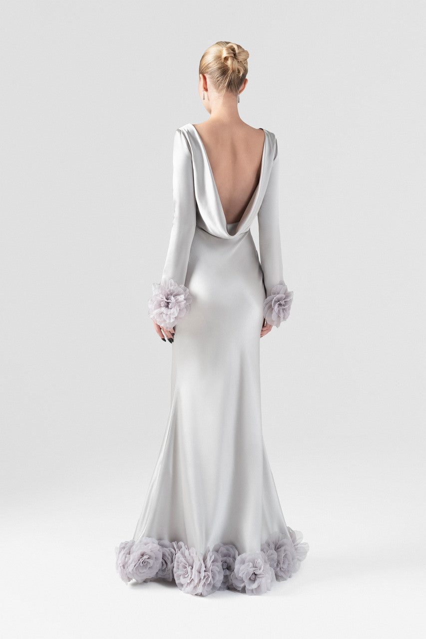 The grey silk maxi dress with mermaid silhouette, plunging open back, and handcrafted floral details at the hem and cuffs.