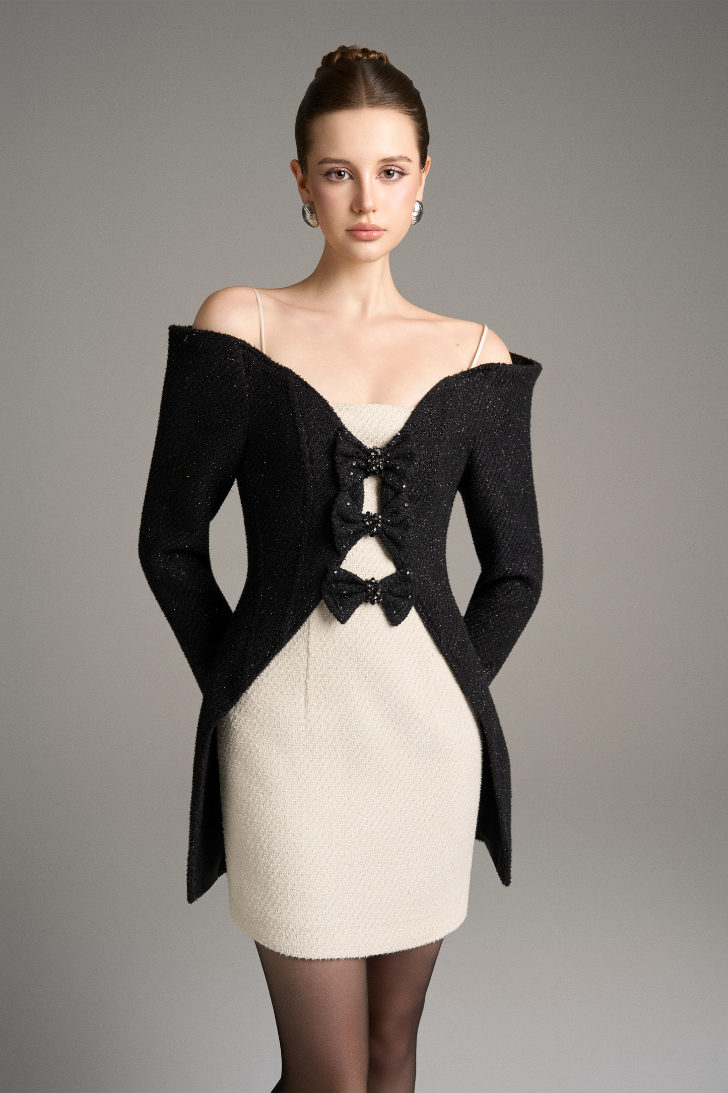 Woman wearing a black off-shoulder jacket over a white dress
