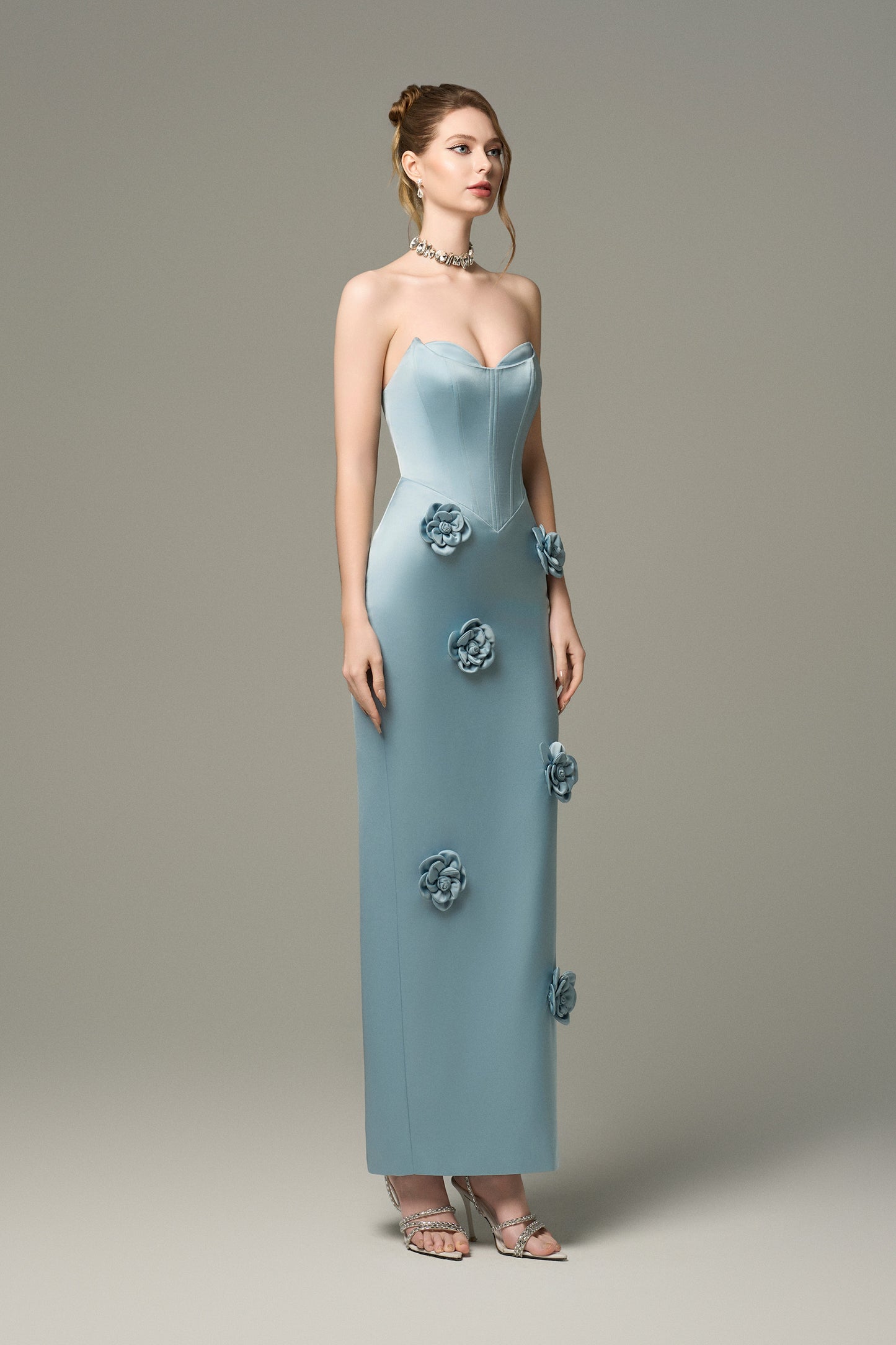 The Turquoise Silk Floral Applique Maxi Dress is crafted from high-quality silk, featuring hand-sewn 3D floral appliqués cascading down the skirt