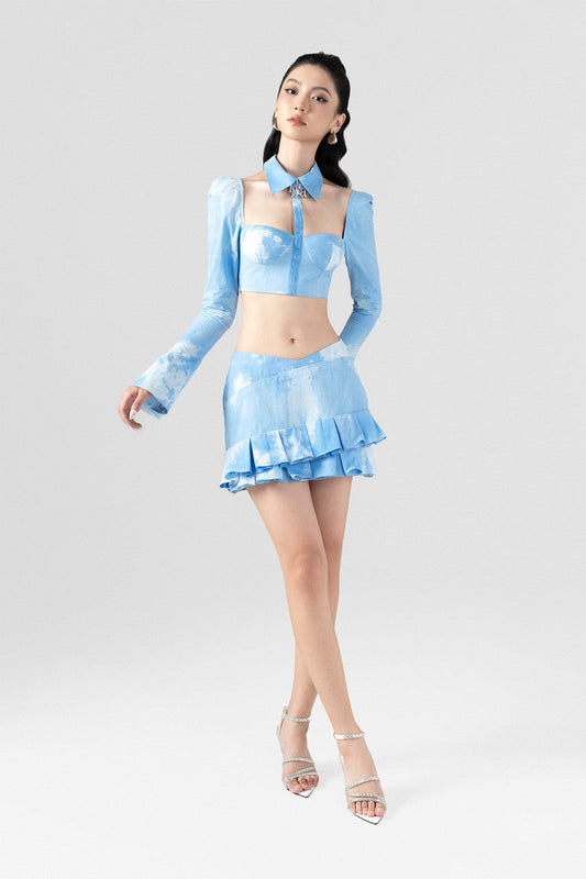 A high-neckline crop top with daring cut-outs and a layered mini skirt in premium blue cotton.
