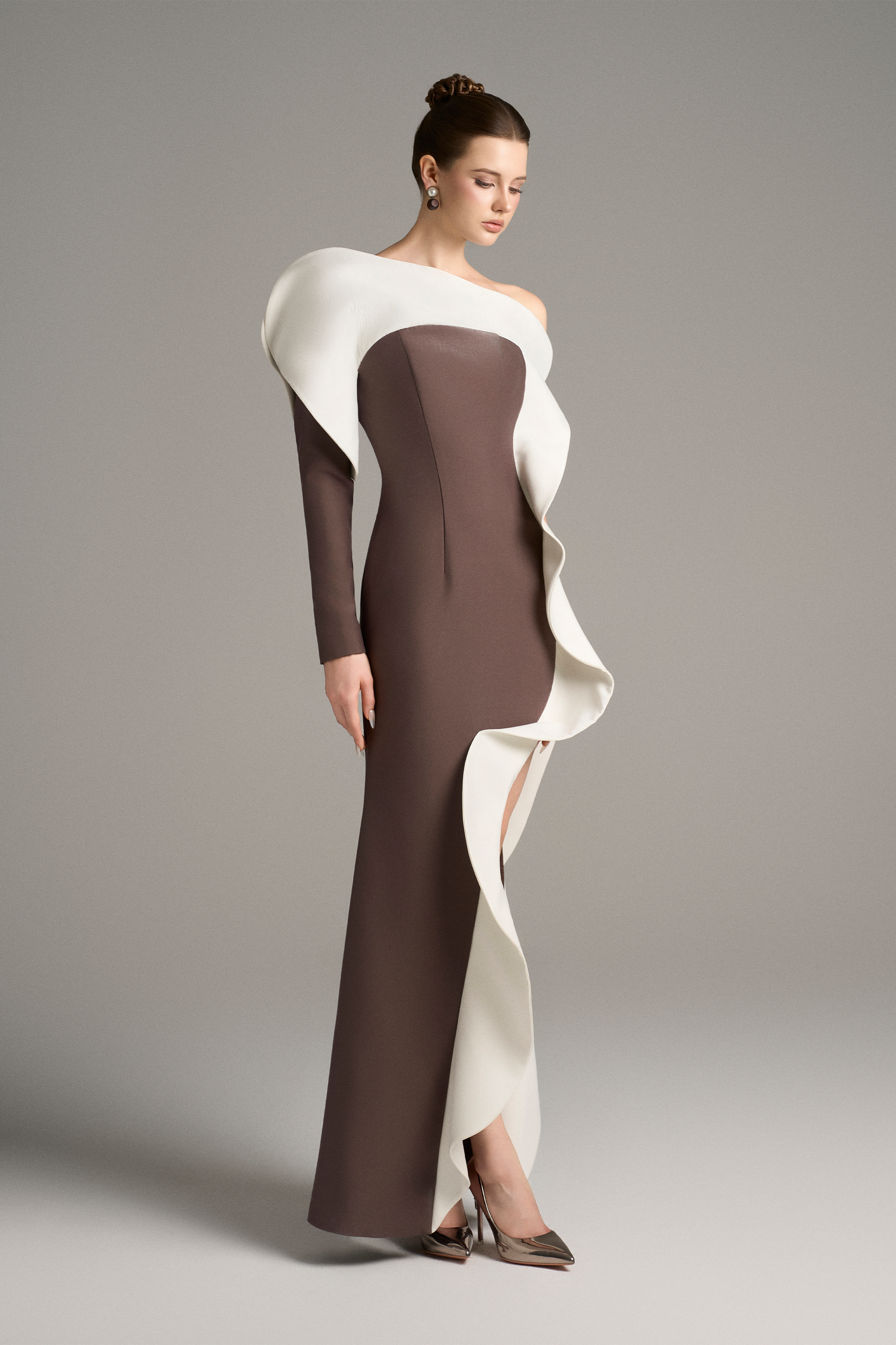 Three-quarter view of the model wearing the gown, showcasing the one-shoulder design and bold white wave-like trim along the front slit.