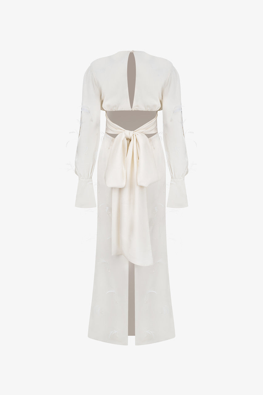 A beige silk maxi dress, adorned with intricate embellishments of feathers, pearls, and crystals. 