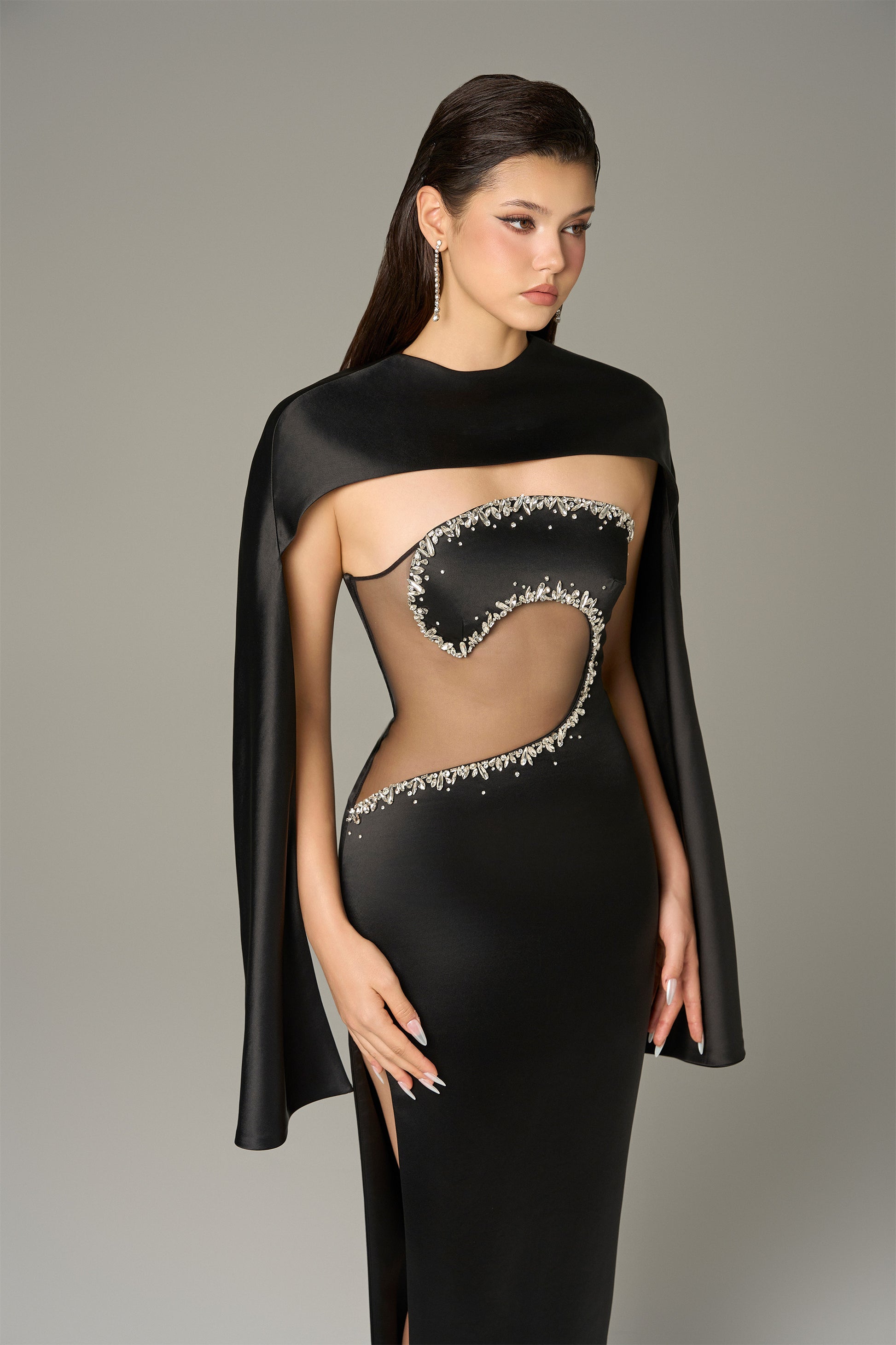 The Black Front Cut Out Gown features a daring cut-out with shimmering stone details.