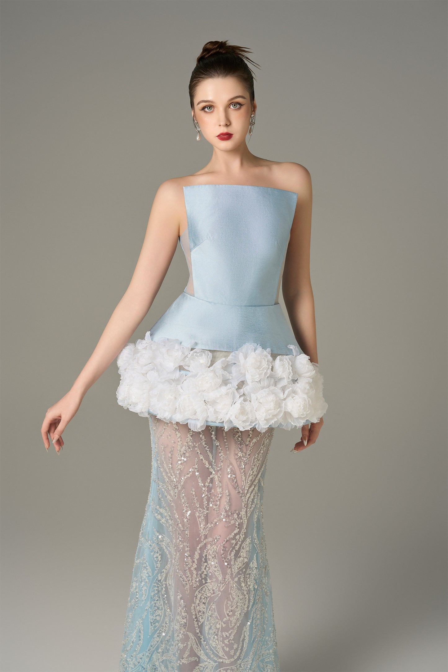 The Blue Gown stuns with a strapless bodice and shimmering lace skirt and handcrafted floral appliqués.
