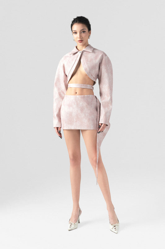 A pink leather set featuring a slim-fit blazer with oversized sleeves, an inverted V-cut neckline, and a matching mini skirt with a side flap.