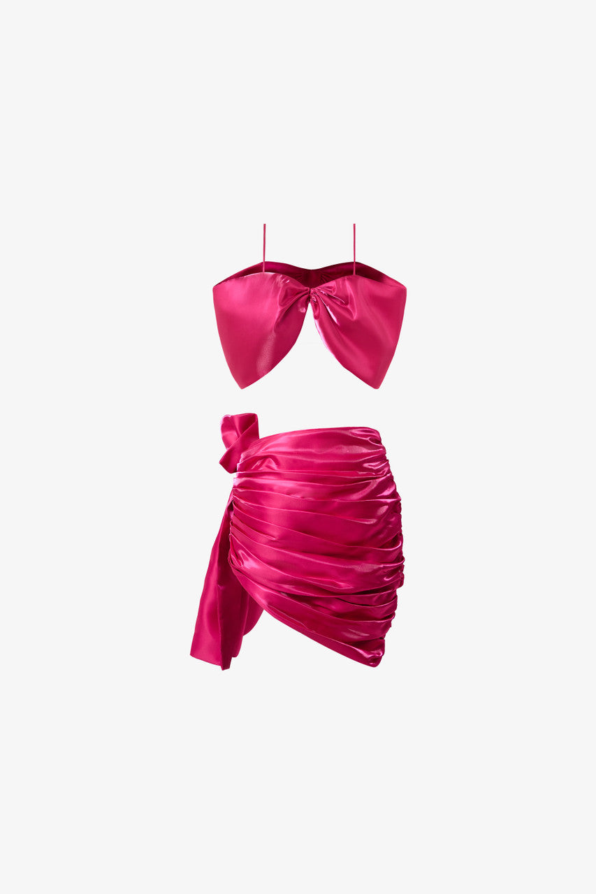 A bow-shaped crop top paired with a ruffle trim draped skirt. Available in rich red and pink.