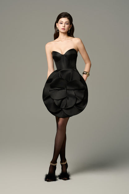 Black strapless dress with a structured corset bodice and a floral applique at the front.