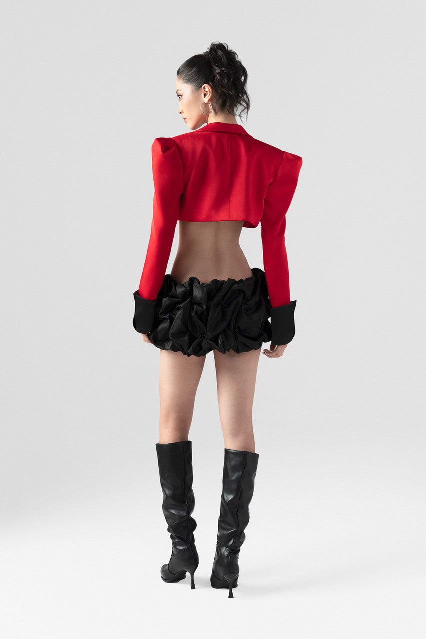 a red crop blazer and a draped black mini skirt with a crystal embellished belt. 