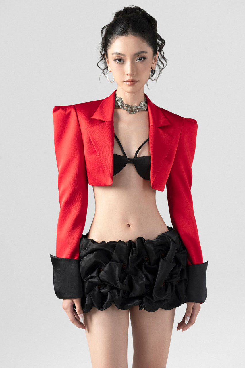 a red crop blazer and a draped black mini skirt with a crystal embellished belt. 