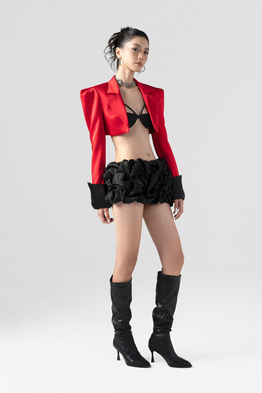 a red crop blazer and a draped black mini skirt with a crystal embellished belt. 