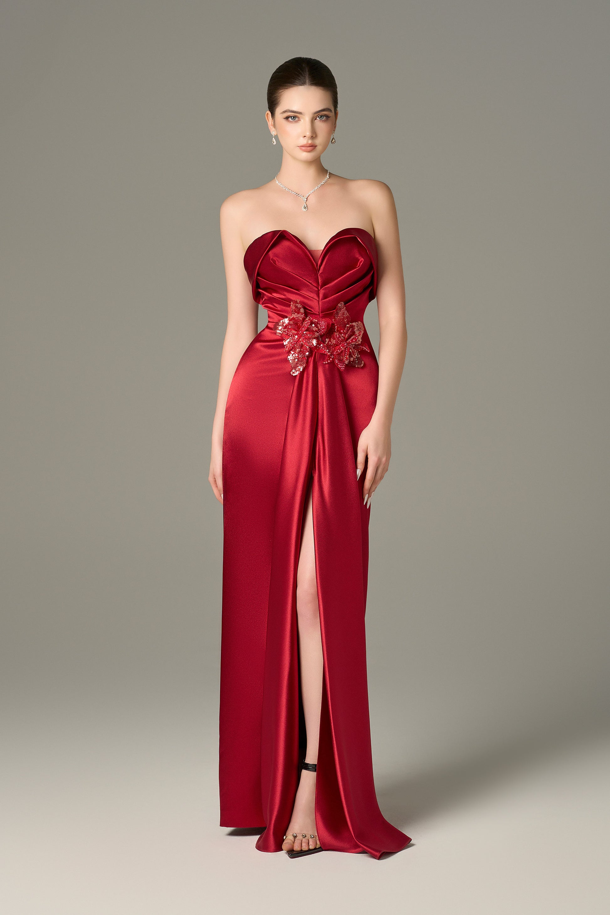 The Red Satin Silk Maxi Dress stuns with a 3D pleated heart bodice, sequin floral details and a  thigh-high slit.