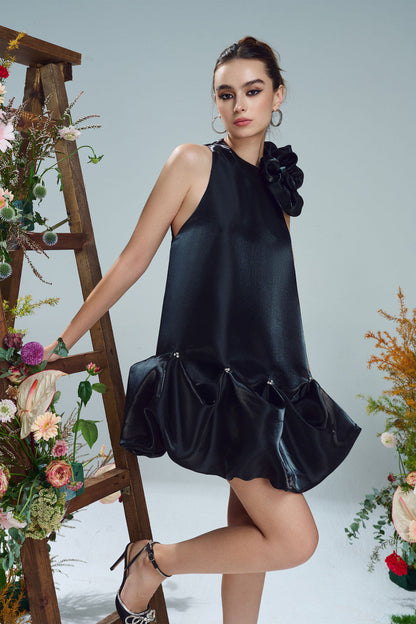 The black mini dress, featuring a oversized floral accent at the neckline and a bubble hem. 