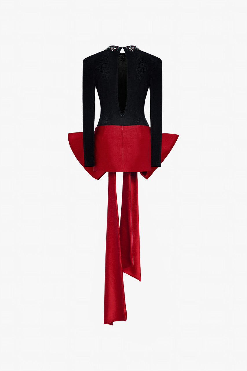 A sleek black fitted top with a beaded round neckline and cut-out back, and a red skirt adorned with an oversized bow. 