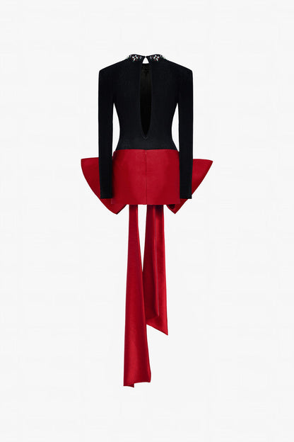 A sleek black fitted top with a beaded round neckline and cut-out back, and a red skirt adorned with an oversized bow. 